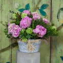 Cubo de zinc y flores en tonos rosas